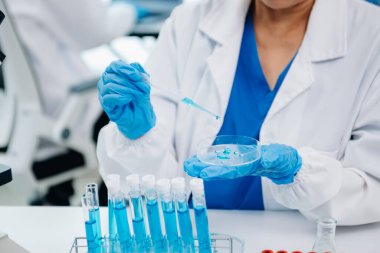 Bir tıp laboratuarında araştırma yapan bilim adamları, ön plandaki bir araştırmacı tıp laboratuvarında bir mikroskop kullanıyor.. 