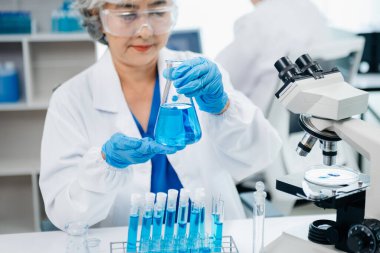 Bir tıp laboratuarında araştırma yapan bilim adamları, ön plandaki bir araştırmacı tıp laboratuvarında bir mikroskop kullanıyor.. 