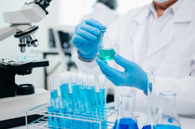 Bir tıp laboratuarında araştırma yapan bilim adamları, ön plandaki bir araştırmacı tıp laboratuvarında bir mikroskop kullanıyor.. 