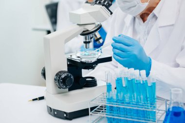 Bir tıp laboratuarında araştırma yapan bilim adamları, ön plandaki bir araştırmacı tıp laboratuvarında bir mikroskop kullanıyor.. 