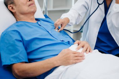 Beyaz takım elbiseli Asyalı doktor, hastanede ya da klinikte salin solüsyonu alan Asyalı yaşlıları ve yatakta yatan hastaları tartışırken not alıyor..