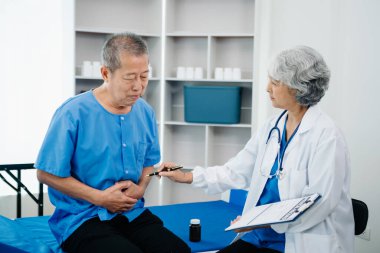 Beyaz takım elbiseli Asyalı doktor, hastanede ya da klinikte salin solüsyonu alan Asyalı yaşlıları ve yatakta yatan hastaları tartışırken not alıyor..