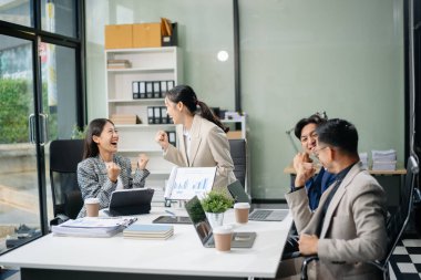 Modern bir ofiste Asyalı profesyoneller arasındaki takım çalışması ve işbirliği, kurumsal kültür, yenilik ve verimliliği gözler önüne seriyor