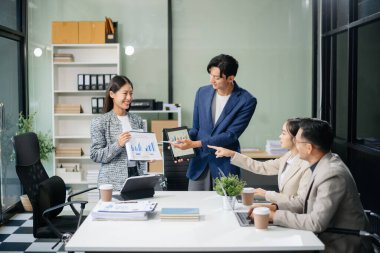 Modern bir ofiste Asyalı profesyoneller arasındaki takım çalışması ve işbirliği, kurumsal kültür, yenilik ve verimliliği gözler önüne seriyor