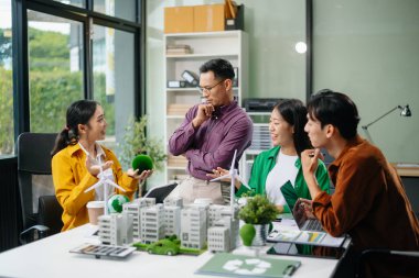 Neare 'de oturan çeşitli etnik çeşitlilikteki işadamları, konut projesinden bir yapı modeline bakıyorlar. Yeşil iş şirketi ve Güneş Enerjisi Çevre Kenti Kavramı.