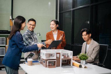 Asyalı mimarlar ve tasarımcılar modern bir ofiste beyin fırtınası yapıyor ve işbirliği yapıyor, modellerden faydalanıyor ve yenilikçi kentsel yapılar tasarlama planları yapıyorlar.