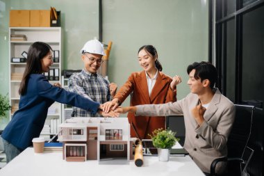 Asyalı mimarlar ve tasarımcılar modern bir ofiste beyin fırtınası yapıyor ve işbirliği yapıyor, modellerden faydalanıyor ve yenilikçi kentsel yapılar tasarlama planları yapıyorlar.