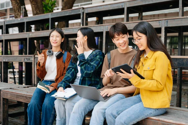 Genç Asyalı üniversite öğrencileri ve bir kız öğrenci grubu sabahları arkadaşlarıyla kampüs parkında çalışıyor. Eğitim kavramı 