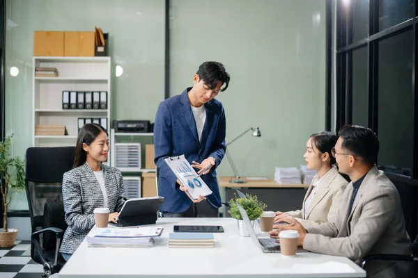 Modern bir ofiste Asyalı profesyoneller arasındaki takım çalışması ve işbirliği, kurumsal kültür, yenilik ve verimliliği gözler önüne seriyor
