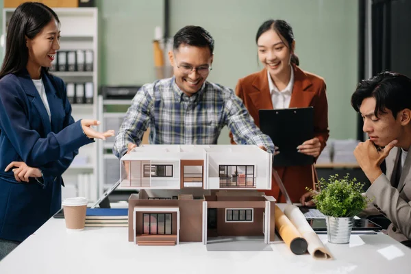 Asyalı mimarlar ve tasarımcılar modern bir ofiste beyin fırtınası yapıyor ve işbirliği yapıyor, modellerden faydalanıyor ve yenilikçi kentsel yapılar tasarlama planları yapıyorlar.