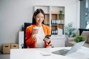 Young beautiful woman using laptop and tablet while sitting at her working place. Concentrated at work