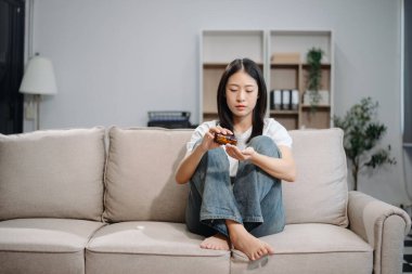 Asyalı kadın Buhran 'da oturur. Koyu saçlı, dalgın bakışlı. Pencere ve anksiyete dolu. Hastalık, sağlık ve iyileşme kavramı.
