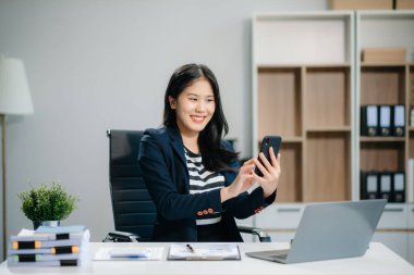 Ofiste çalışan genç bir iş kadını dizüstü bilgisayarı, tableti ve kağıda not alıyor. modern ofiste.