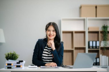 Ofiste çalışan genç bir iş kadını dizüstü bilgisayarı, tableti ve kağıda not alıyor. modern ofiste.