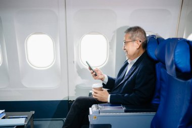 Asyalı üst düzey yönetici, dijital tablet, dizüstü bilgisayar ve akıllı telefonla birden fazla iş yapma konusunda birinci sınıf bir yönetici. Stil içinde seyahat et, zarafetle çalış..