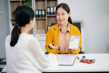 Asyalı araba satıcısı veya satış müdürü araba satmayı teklif ediyor ve bir araba sözleşmesi imzalamayı ve araba sigortası belgesi imzalamayı veya kira kağıdını açıklıyor