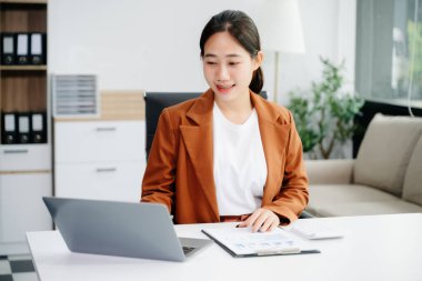 Güzel Asyalı kadın çalıştığı yerde bilgisayarını ve tabletini kullanıyor. İşine odaklan..