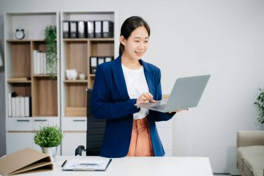 Güzel Asyalı kadın çalıştığı yerde bilgisayarını ve tabletini kullanıyor. İşine odaklan..