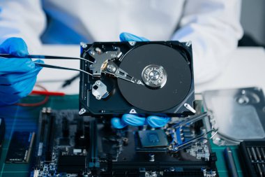 Teknisyenin masasında sabit disk ve bir bilgisayar ana kartı var. Veri konsepti, donanım teknolojisi