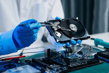 Teknisyenin masasında sabit disk ve bir bilgisayar ana kartı var. Veri konsepti, donanım teknolojisi