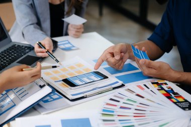 UI geliştirici ekibi dizüstü bilgisayarları, akıllı telefonları ve dijital tabletleriyle projelerinde beyin fırtınası yapıyorlar. Yaratıcı dijital geliştirme ajansı. Ofiste