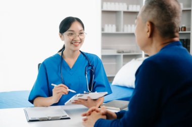 Pano kullanan Asyalı kadın doktor harika haberler sunuyor. Klinikteki veya hastane ofisindeki erkek hastalarla sonuçları ya da belirtileri tartışıyor.