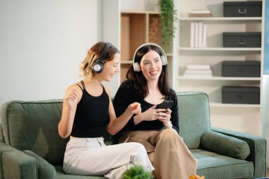Two women collaborating on a project at home, brainstorming with a laptop and notebook in a cozy setting. Perfect for teamwork, remote work, and productivity themes