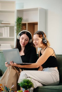 Evde bir projede işbirliği yapan iki kadın, samimi bir ortamda dizüstü bilgisayar ve defterle beyin fırtınası yapıyorlar. Takım çalışması, uzaktan çalışma ve üretkenlik temaları için mükemmel