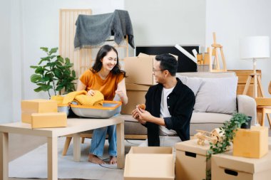 Büyük kutuları olan Asyalı genç ve çekici bir çift yeni bir eve taşınıyor, yeni bir çift için yeni bir daire, taşınma evi. sof