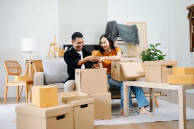 Büyük kutuları olan Asyalı genç ve çekici bir çift yeni bir eve taşınıyor, yeni bir çift için yeni bir daire, taşınma evi. sof