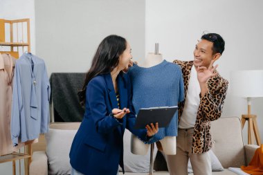 İki profesyonel Asya 'lı genç bayan moda tasarımcısı masa kullanım tableti toplantısında günlük site ile birlikte mağazada tasarım paylaşımı fikrini tartıştılar. Levhaları tutuyor.