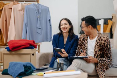 İki profesyonel Asya 'lı genç bayan moda tasarımcısı masa kullanım tableti toplantısında günlük site ile birlikte mağazada tasarım paylaşımı fikrini tartıştılar. Levhaları tutuyor.