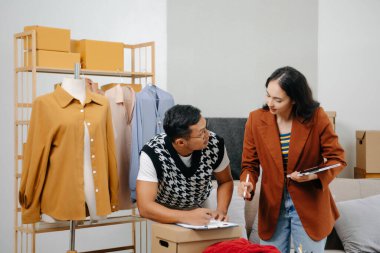 İki profesyonel Asya 'lı genç bayan moda tasarımcısı masa kullanım tableti toplantısında günlük site ile birlikte mağazada tasarım paylaşımı fikrini tartıştılar. Levhaları tutuyor.