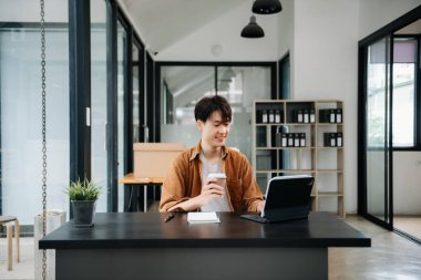 Ofisteki masasında oturan Asyalı genç bir adamın portresi..