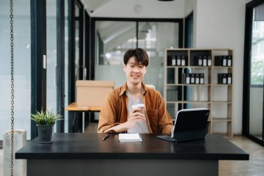 Ofisteki masasında oturan Asyalı genç bir adamın portresi..