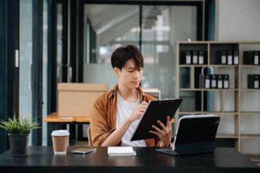 Ofisteki masasında oturan Asyalı genç bir adamın portresi..