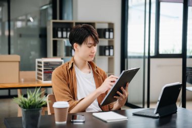 Ofisteki masasında oturan Asyalı genç bir adamın portresi..
