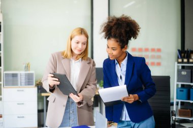 İş kadını takım toplantısını yönetiyor ve birlikte çalışma ofisinde mali durumuyla birlikte tablet ve dizüstü bilgisayar kullanıyor