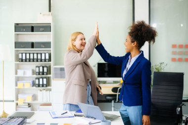 İş kadını takım toplantısını yönetiyor ve birlikte çalışma ofisinde mali durumuyla birlikte tablet ve dizüstü bilgisayar kullanıyor