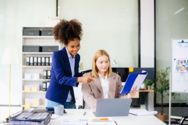 İş kadını takım toplantısını yönetiyor ve birlikte çalışma ofisinde mali durumuyla birlikte tablet ve dizüstü bilgisayar kullanıyor