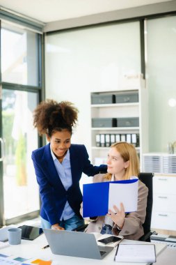 İş kadını takım toplantısını yönetiyor ve birlikte çalışma ofisinde mali durumuyla birlikte tablet ve dizüstü bilgisayar kullanıyor