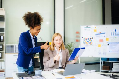 İş kadını takım toplantısını yönetiyor ve birlikte çalışma ofisinde mali durumuyla birlikte tablet ve dizüstü bilgisayar kullanıyor