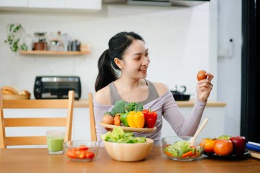 Modern bir mutfakta, taze meyve, sebze, blender ve meyve suyuyla gülümseyen bir kadın. Temiz yemek, sağlıklı yaşam ve hayat dolu bir yaşam tarzı..