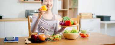 Modern bir mutfakta, taze meyve, sebze, blender ve meyve suyuyla gülümseyen bir kadın. Temiz yemek, sağlıklı yaşam ve hayat dolu bir yaşam tarzı..