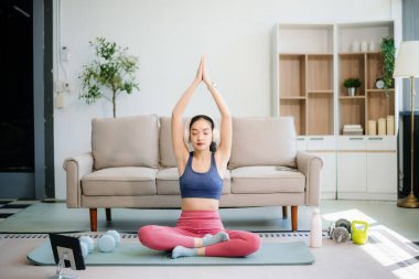 Genç bir kadın yoga yaparken ve spor malzemeleriyle çevrili bir mindere gerilirken, sağlığını, farkındalığını gösterirken, sağlığın özünü yakalayın.