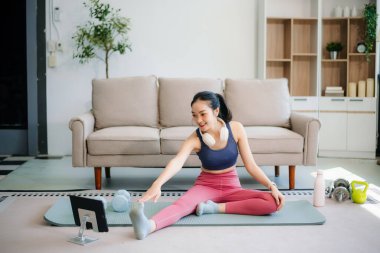 Genç bir kadın yoga yaparken ve spor malzemeleriyle çevrili bir mindere gerilirken, sağlığını, farkındalığını gösterirken, sağlığın özünü yakalayın.