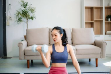 Genç bir kadın yoga yaparken ve spor malzemeleriyle çevrili bir mindere gerilirken, sağlığını, farkındalığını gösterirken, sağlığın özünü yakalayın.