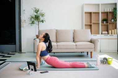 Genç bir kadın yoga yaparken ve spor malzemeleriyle çevrili bir mindere gerilirken, sağlığını, farkındalığını gösterirken, sağlığın özünü yakalayın.