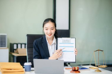 Adalet ve profesyonellik dünyası. Ofis masasında yasal belgeleri elinde tutan genç bir kadın avukatın bu zarif görüntüsü.