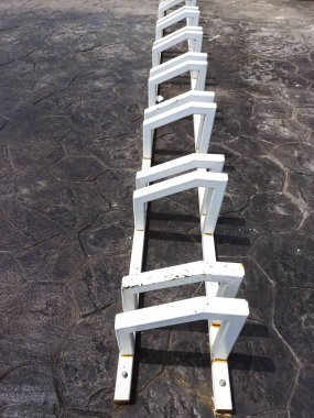 Boş beyaz bisiklet parkı koyu renkli, damgalı beton kaldırıma sabitlenmiş. Bisiklet ve ulaşım için kentsel altyapıya yakın çekim.
